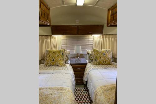 a bedroom with two beds and a table with a lamp at Beautiful Airstream, Beaufort SC-Enjoy the Journey in Beaufort
