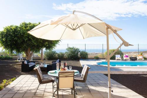 a patio with a table and an umbrella next to a pool at Apartment Private Heated Pool in El Draguito