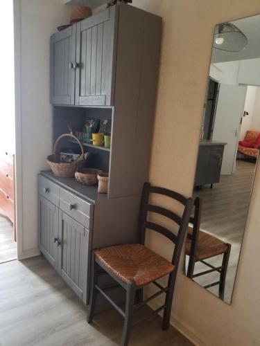 une cuisine avec une chaise, un comptoir et une armoire dans l'établissement Appartement dans la verdure près des plages, à Saint Cyprien Plage
