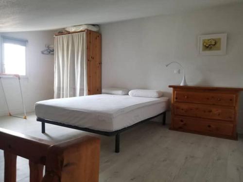 a bedroom with a bed and a wooden dresser at Appartement dans la verdure près des plages in Saint-Cyprien-Plage
