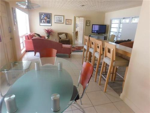 uma sala de jantar e sala de estar com uma mesa de vidro e cadeiras em Dolphin Isles Resort em Fort Lauderdale