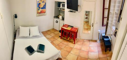 トゥールーズにあるStudio des Carmesのベッドとテーブルが備わる小さな客室です。