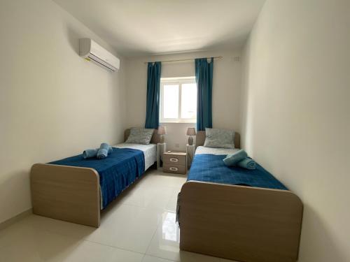 a bedroom with two beds and a window at Sunshine Apartments Mellieha - modern three bedroom apartment - Apt No 3 in Mellieħa