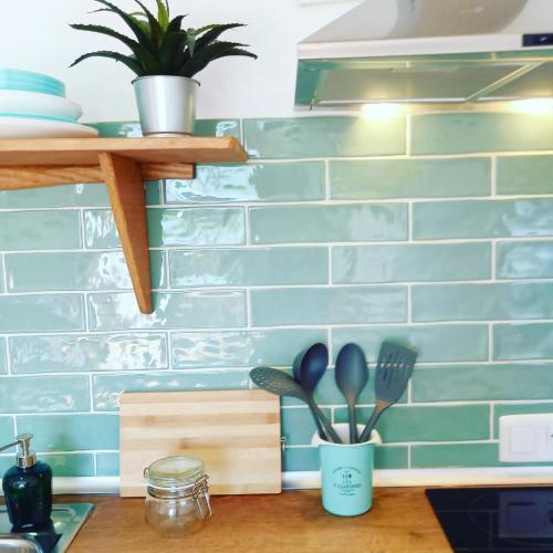 a kitchen counter with a blue brick wall with utensils at Agua Amarga Design in Agua Amarga