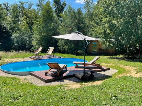 a swimming pool with two chairs and an umbrella at Boutique Glamping Divja DiVine in Zgornja Korena