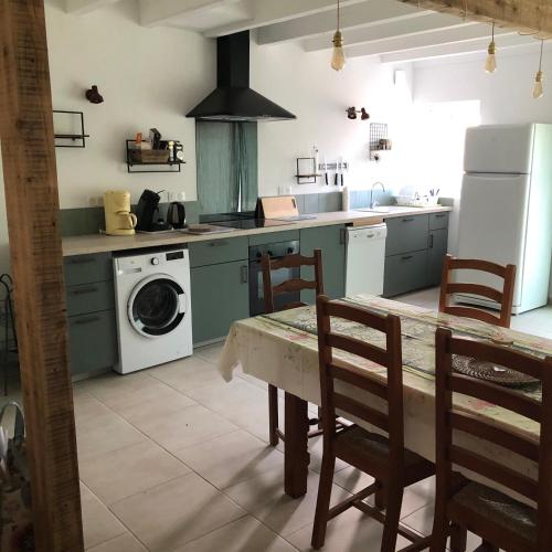 a kitchen with a table and a washing machine at Manoir de Champvert in Les Vans