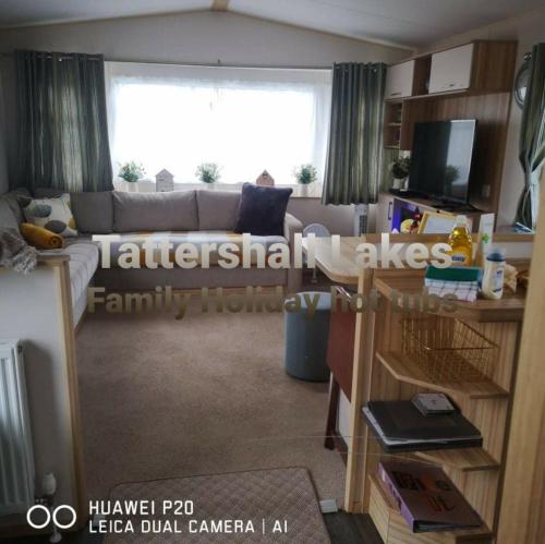 a living room with a couch and a large window at Tattershall Lakes Family Holiday Hot Tub break in Tattershall