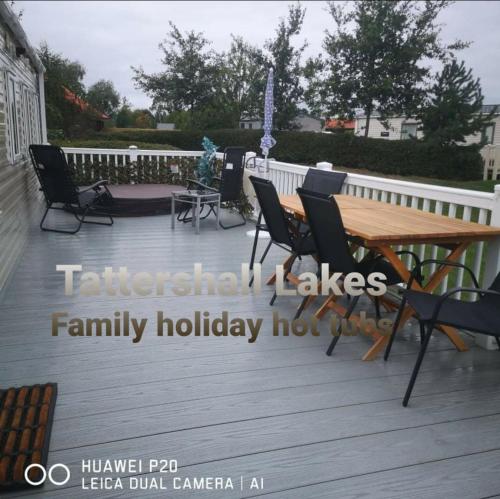 a wooden deck with a wooden table and chairs at Tattershall Lakes Family Holiday Hot Tub break in Tattershall