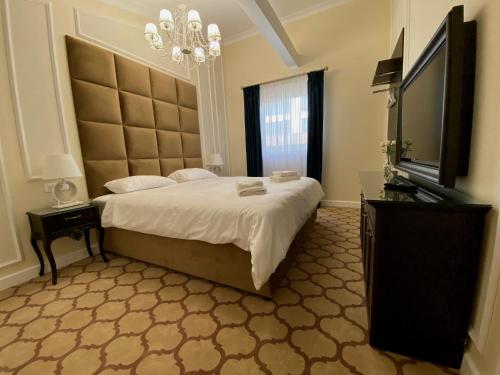 een slaapkamer met een groot bed en een flatscreen-tv bij Venetian Bucharest in Boekarest