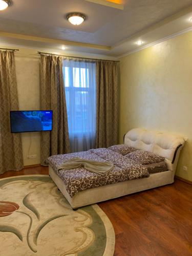 a bedroom with a large bed and a television at Apartment Miskevycha in Lviv