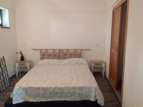 a bedroom with a white bed and two tables at Dammuso Dell`Angelo in Pantelleria