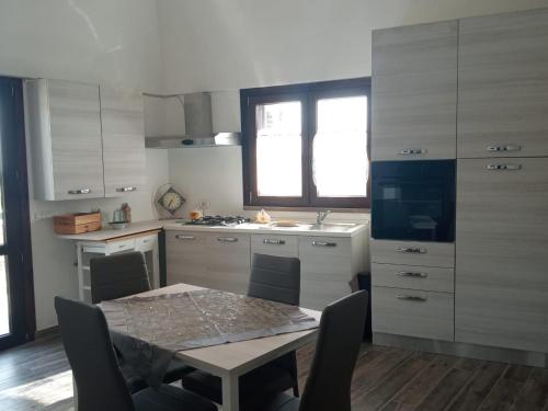 una cucina con tavolo e sedie e una cucina con armadietti bianchi di Dammuso Dell`Angelo a Pantelleria