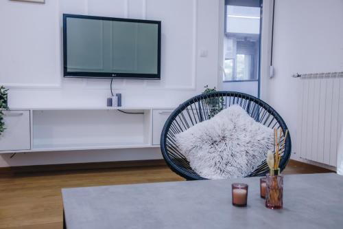 a living room with a table with a chair and a tv at LUST PREMIUM Apartments in Kragujevac