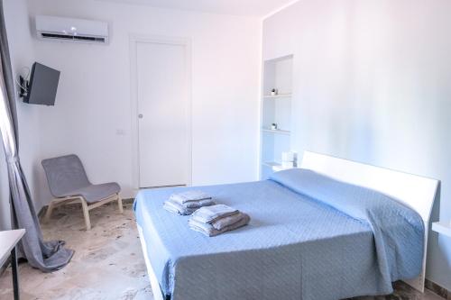 a bedroom with a bed with blue sheets and a chair at Villa Kola B&B in Agrigento