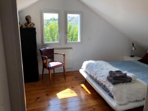 una camera con un letto e una sedia e una finestra di Chambre hôtes nichée sous les toits a Rennes