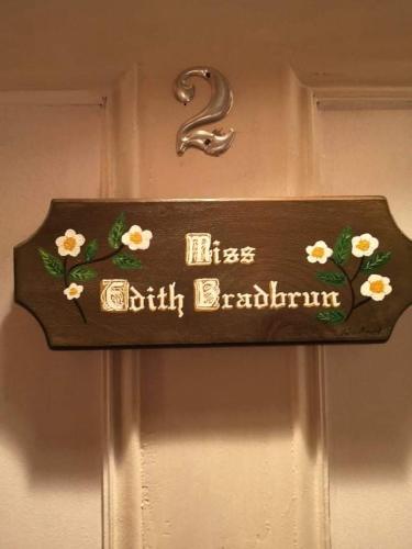 a sign on a door with flowers on it at Gite de la Baie Hatée in Bic