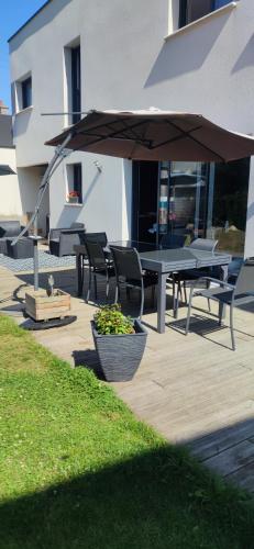 eine Terrasse mit Tischen, Stühlen und einem Sonnenschirm in der Unterkunft TY SAM BELLE MAISON MODERNE 8 à 10 personnes - PROCHE plages et commerces in Trébeurden