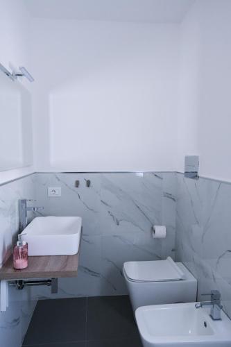 a white bathroom with a sink and a toilet at Villa Kola B&B in Agrigento