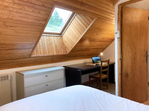 a attic bedroom with a desk and a window at L'Orée des Pignes in Nojaret