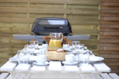 a white picnic table with glasses and a toaster at L'Orée des Pignes in Nojaret