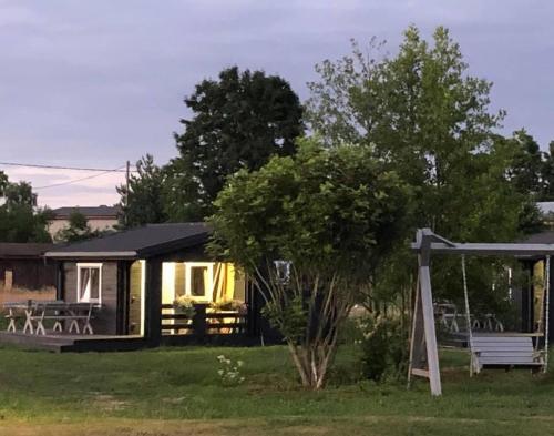 a tiny house with a porch and a swing at Ragaciema Skadiņi in Ragaciems