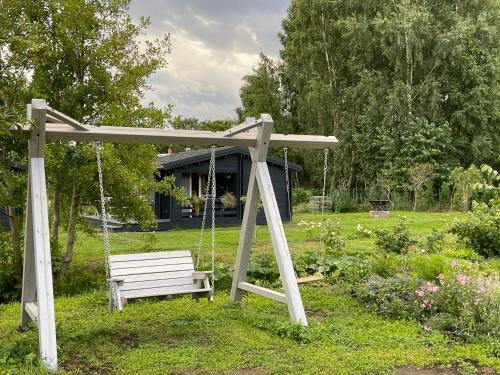 a swinging bench in a yard with a house at Ragaciema Skadiņi in Ragaciems
