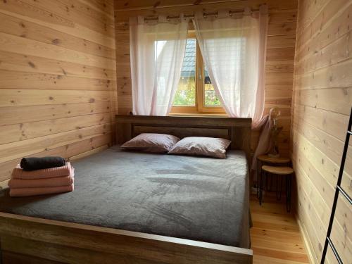 a bed in a wooden room with a window at Ragaciema Skadiņi in Ragaciems