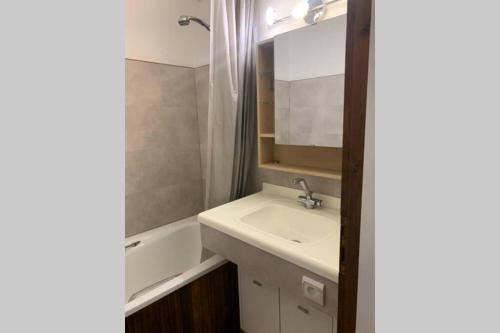 La salle de bains est pourvue d'un lavabo et d'une baignoire. dans l'établissement Superbe appartement avec parking gratuit sur place, à Bourg-Saint-Maurice