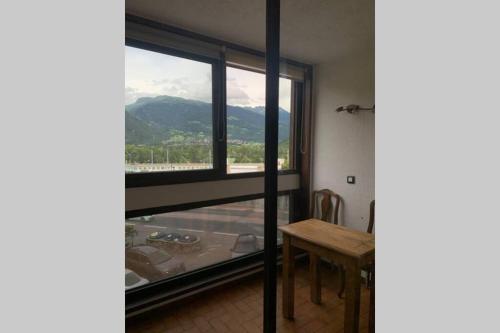 Cette chambre dispose d'une table et d'une grande fenêtre. dans l'établissement Superbe appartement avec parking gratuit sur place, à Bourg-Saint-Maurice