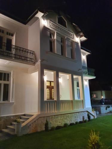 a large white house with lights on it at night at Vila Samokres sa bazenom in Banja Koviljača