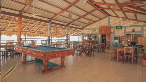 ein Billardtisch in einem Restaurant mit Tischen und Stühlen in der Unterkunft The Barrel Hostel in Popoyo