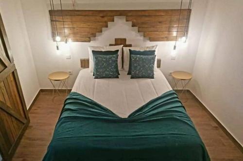 1 dormitorio con 1 cama grande con sábanas verdes y 2 mesas en Cantinho D'aldeia - Casa Rural com Jacuzzi, en Guarda