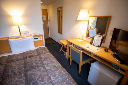 a hotel room with a bed and a desk with a computer at AZ Inn Handa Inter in Handa