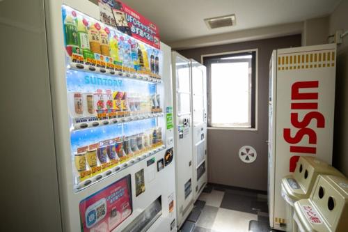 a refrigerator in a room with a soda machine at AZ Inn Handa Inter in Handa