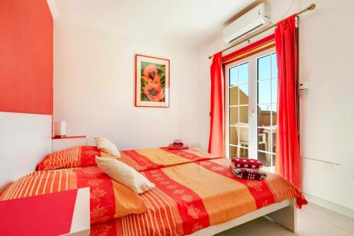 een slaapkamer met een bed met rode gordijnen en een raam bij Remarkable 2-Bed House in Arona in Arona