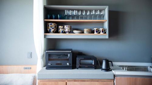 a kitchen with a counter with a toaster and a microwave at Feliz Villa Suite Kourijima View in Nago