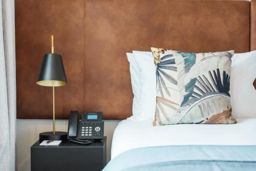 a bedroom with a bed with a lamp and a phone at Quest Takapuna in Auckland