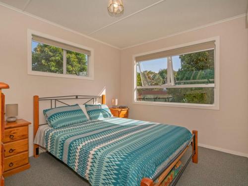 a bedroom with a bed and two windows at Hosts on the Coast Whiti Delight in Whitianga