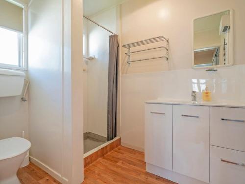 a white bathroom with a shower and a toilet at Hosts on the Coast Whiti Delight in Whitianga