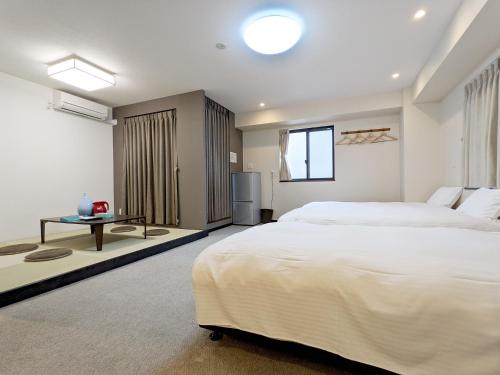 een slaapkamer met een groot wit bed en een tafel bij KYU KYU HOTEL in Tokyo