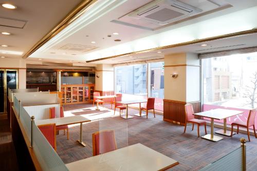 een restaurant met tafels en stoelen en grote ramen bij Hotel Resol Sasebo in Sasebo