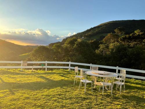 einen Tisch und Stühle auf dem Rasen in der Nähe eines Zauns in der Unterkunft Casa de campo Recanto Pedra Azul in Baependi