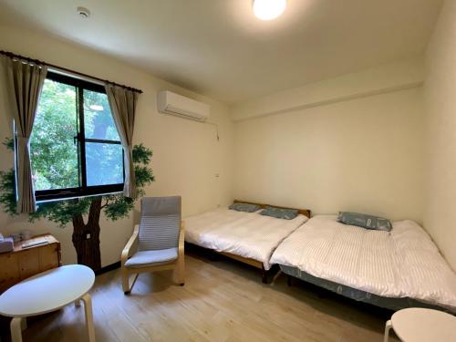 1 dormitorio con 2 camas, silla y ventana en Tree House Café & Homestay, en Tongluo