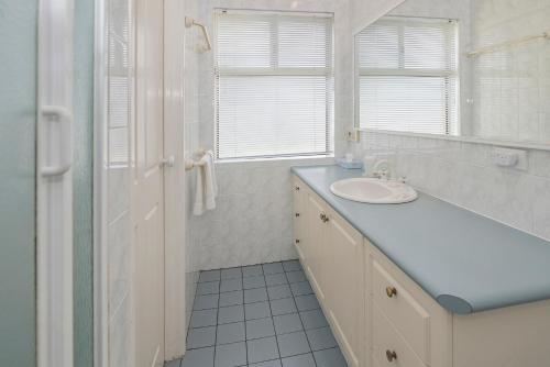 a white bathroom with a sink and a mirror at Bella Beach House Prevelly 50m from the beach in Prevelly