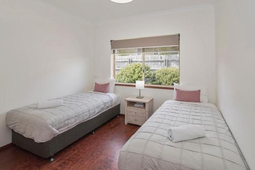 two beds in a room with a window at Bella Beach House Prevelly 50m from the beach in Prevelly