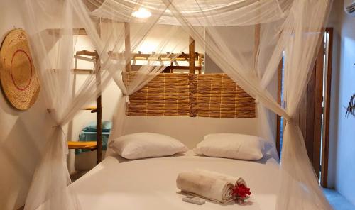 a bedroom with a bed with white drapes at Chalé Vera Ar condicionado Pousada 35knots Brasil in Luis Correia