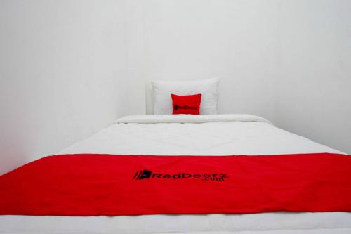 a red and white bed with a red pillow on it at RedDoorz near GOR Jatidiri Semarang in Jatingaleh