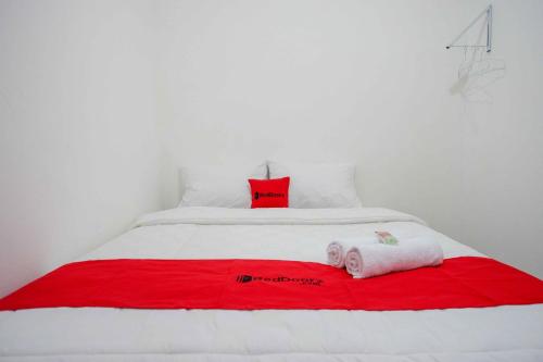 a white bed with red and white towels on it at RedDoorz near GOR Jatidiri Semarang in Jatingaleh