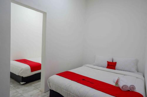 a bedroom with two beds with red and white sheets at RedDoorz near GOR Jatidiri Semarang in Jatingaleh