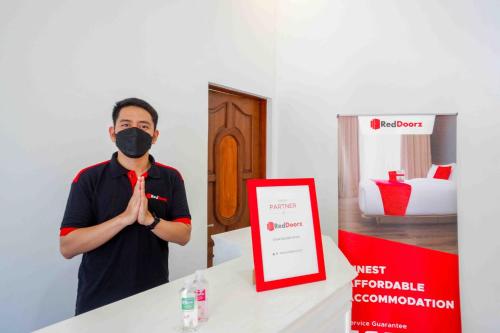 a man wearing a mask standing next to a counter at RedDoorz near GOR Jatidiri Semarang in Jatingaleh